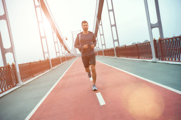 Never give up Full length of young and handsome bearded man in sports clothing jogging on the bridge in the morning