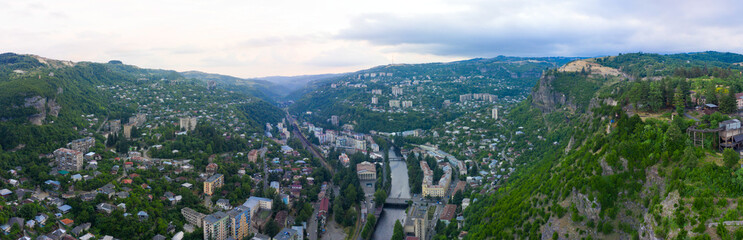 Old rusty and functioning ropeway or cable car cabins in Chiatura. Panorama of the city district and apartment buildings on the rock and Mine at Ropeway station Rgani.