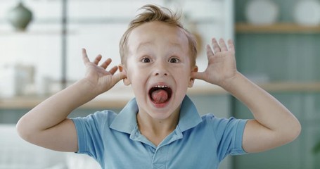 FIXED Portrait of little cute Caucasian kid boy doing silly funny face, looking into camera. 60 FPS Slow Motion, 4K RAW graded footage