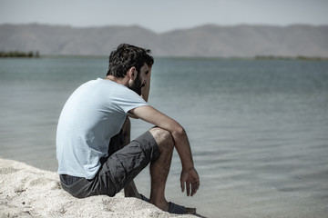 young man sitting on the shore