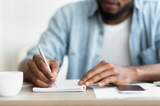 African american businessman writing down his plans to notepad