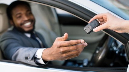 Car salesman giving keys to happy man