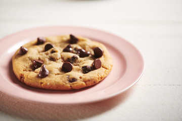 Chocolate Chip Cookie on Pink Plate and Rustic White Surface