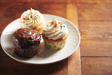 Rainbow Sprinkle Cupcakes on White Plate and Wood Background