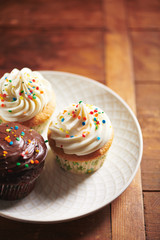 Rainbow Sprinkle Cupcakes on White Plate and Wood Background