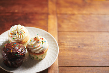 Rainbow Sprinkle Cupcakes on White Plate and Wood Background