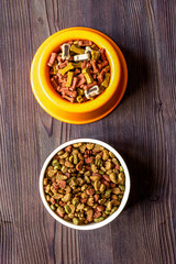 dry dog food in bowl on wooden background top view
