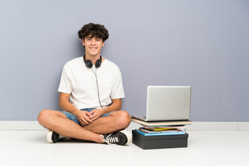 Young man with his laptop sitting one the floor laughing