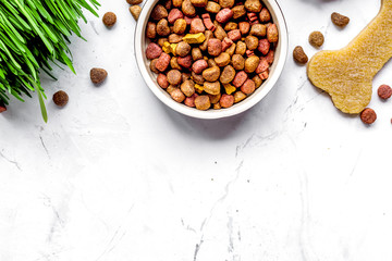 dry dog food in bowl on stone background top view