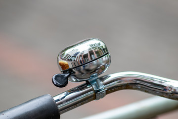 Obraz premium Verchromte und glänzend-polierte Fahrradklingel mit schöner Spiegelung vor unscharfem Hintergrund lädt zum Radfahren und umweltfreundlichen Radeln ein