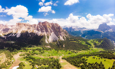 Aerial top view from drone to Col Raiser plateau In sunny summer Day. Scenery of rugged Sella Mountain with green valley on grassy hillside village St. Cristina di Val Gardena, Bolzano, Seceda Italy.