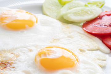 Breakfast - fried eggs and tomato in white plate. Close up image.