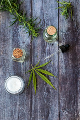 Cannabis hemp creams with marijuana leaf on wooden background - topical cannabis oil concept