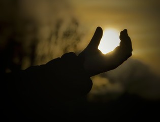 silhouette of hand on a background of blue sky