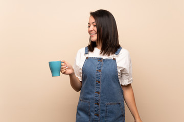 Young Mexican woman over isolated background holding hot cup of coffee