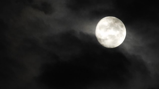 Moon With Clouds In The Night Sky. Concept of a spooky theme and mystery. Mysterious night sky with moon and dramatic clouds passing. Dark night with moon.