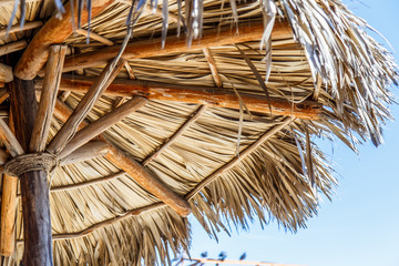 Straw beach umbrella with blue sky closeup