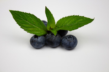 Blueberries on a white background. Ripe blueberries with green leaves with copy space for text. Blueberries on a white background. Copyspace