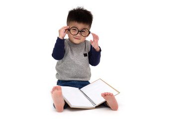 Portrait of a cute Asian little boy wearing glasses sitting on floor and reading a book isolated over white background, Back to school concept, 1 year 10 month old