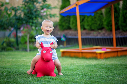 Little Toddler Child, Boy, Riding Plastic Horse Toy In Backyard