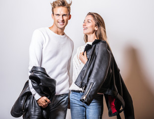 Young beautiful couple in black leather jackets pose in studio.