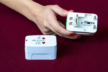 Close up hand hold a universal electric socket plug adapters used for travel. Used to connect to...