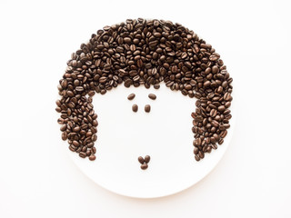 view from above on the face of a woman laid out from coffee beans on a white background
