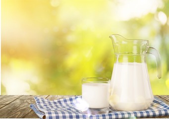 Glass of milk and jar on  background