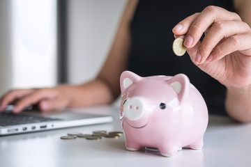 Obraz na płótnie Canvas Woman putting golden coin in pink piggy bank for step up growing business to profit and saving with piggy bank, Saving money for future plan and retirement fund concept