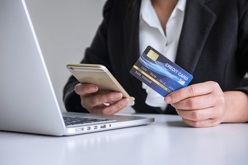 Young woman consumer holding smartphone, credit card and typing on laptop for online shopping and payment make a purchase on the Internet, Online payment, networking and buy product technology