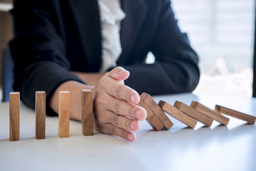Risk and Strategy in Business, Image of hand stopping falling collapse wooden block dominoes effect...