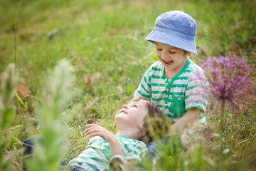 Two boys, brothers, children cuddling in the grass springtime