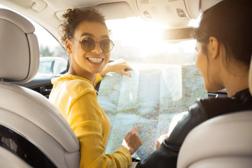 Friends travel by car. Girls looking at map, building route