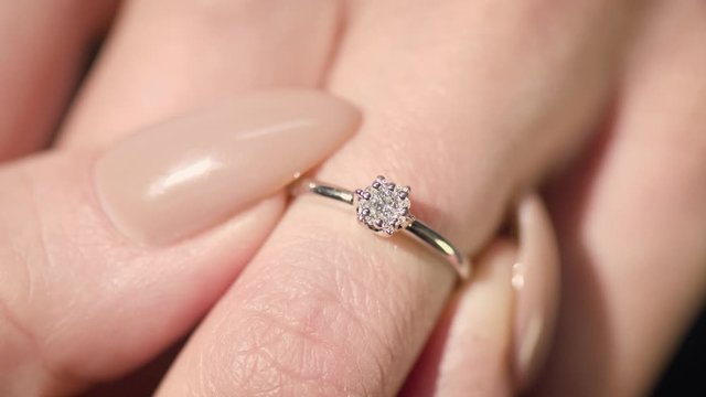 Woman puts a wedding ring on her finger. Close-up view of diamond ring
