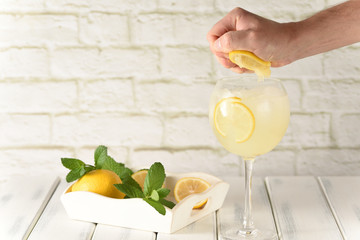 cold refreshing drink with lemon and mint, squeeze lemon by hand