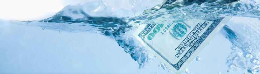 Money concept. US Dollar sinking in water as economic downturn