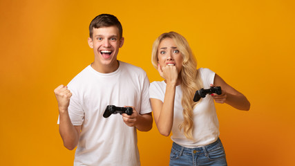 Gambling couple playing video game with joysticks © Prostock-studio