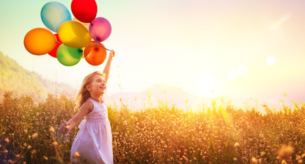 Happy Child Running With Balloons In Field At Sunset
