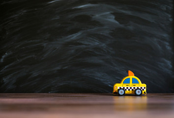 Taxi operator concept. Price of services. Yellow car toy taxi on black background space for text