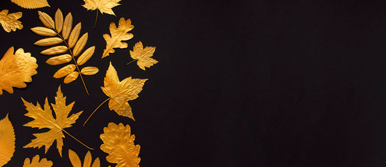 Flat lay creative autumn composition. Golden leaves on black background top view copy space. Fall...