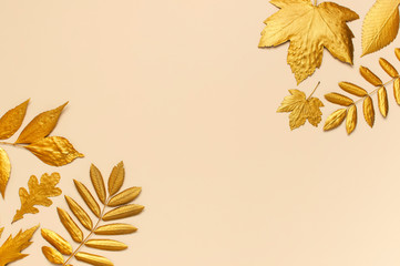 Flat lay creative autumn composition. Frame from Golden leaves on beige background top view copy...