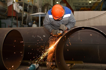 Locksmith processes pipe edge with electric hand grinder