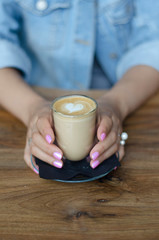 A glass of cappuccino in female hands