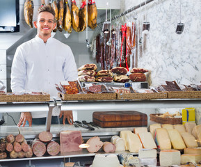 Shop-boy in special clothing shifting sausage