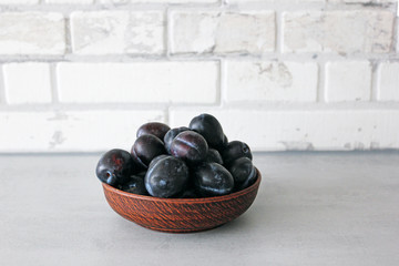 clay bowl with fresh plums in the kitchen in the style of Scandinavian design