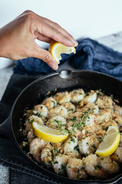 Woman's Hand Squeezing Fresh Lemon Juice On Shrimp Scampi