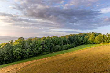 Meadow landscape countryside view with blue sky with many clouds sun light and forest close to city Valasske Mezirici captured during summer late time from hill.