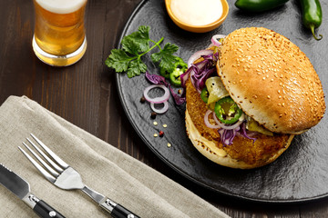 Sandwich made of chicken burger red onion, pickled cucumber, jalapeno and mayonnaise with glass of beer. Top view, directly above shot.