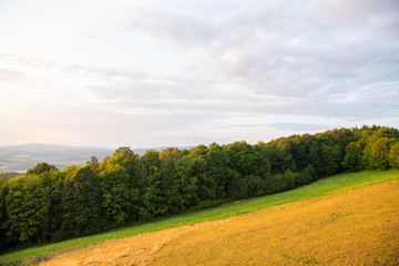 Meadow landscape countryside view with blue sky with many clouds sun light and forest close to city Valasske Mezirici captured during summer late time from hill.