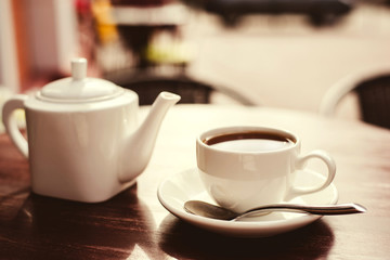 Teapot and cup of tea on wooden table.